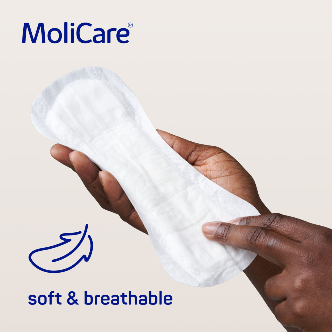MoliCare sanitary pad being held by a hand with 'soft & breathable' text on a beige background