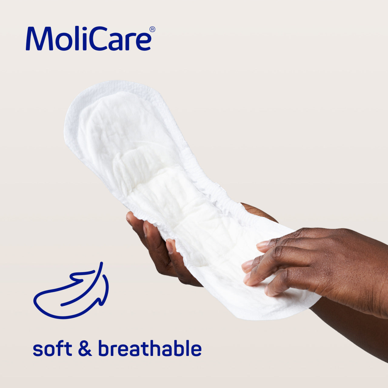 MoliCare product with a hand holding it, labeled 'soft & breathable' on a beige background.