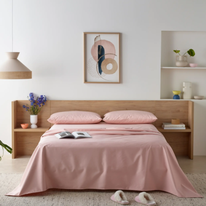 Bedroom with pink bedding and wooden headboard, featuring a framed abstract art piece on the wall.