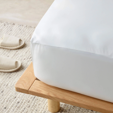 White mattress on a wooden platform with a neutral background