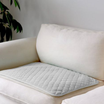 White quilted pillow on a beige sofa with a plant in the background