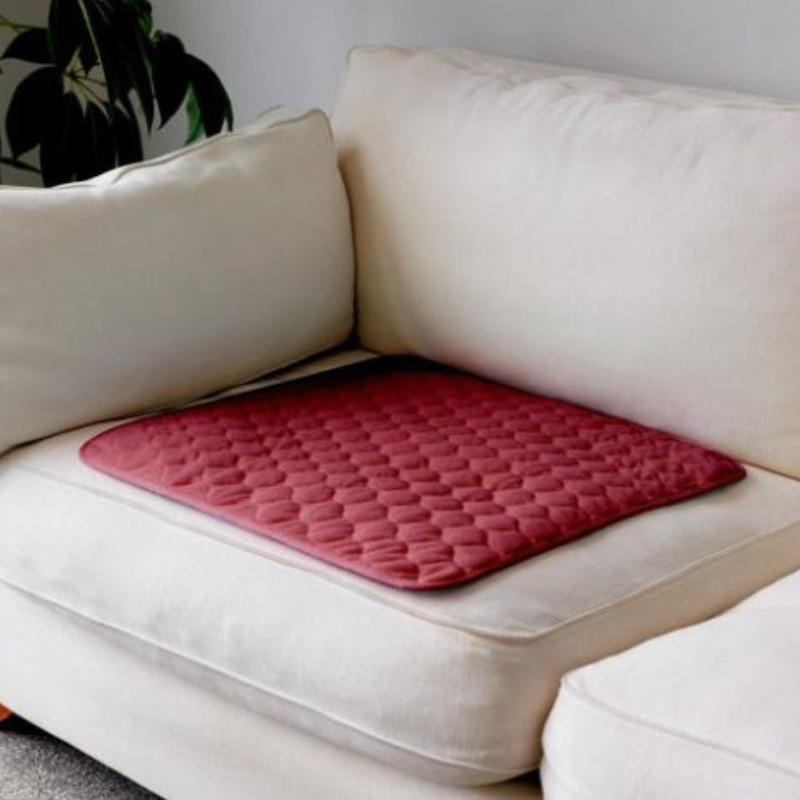Pink quilted mat on a beige sofa with a plant in the background