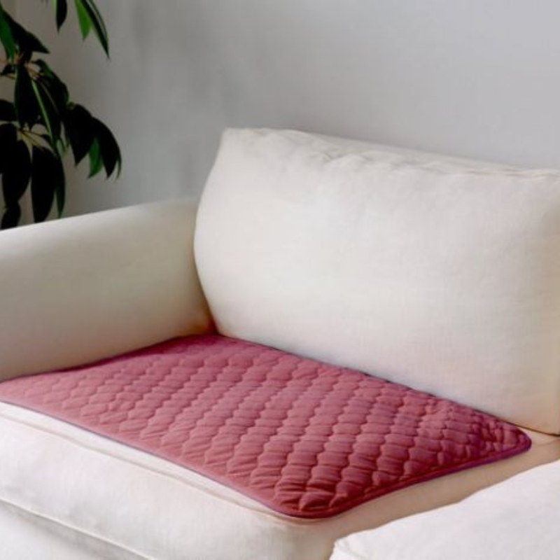 Pink quilted mat on a white sofa with a plant in the background