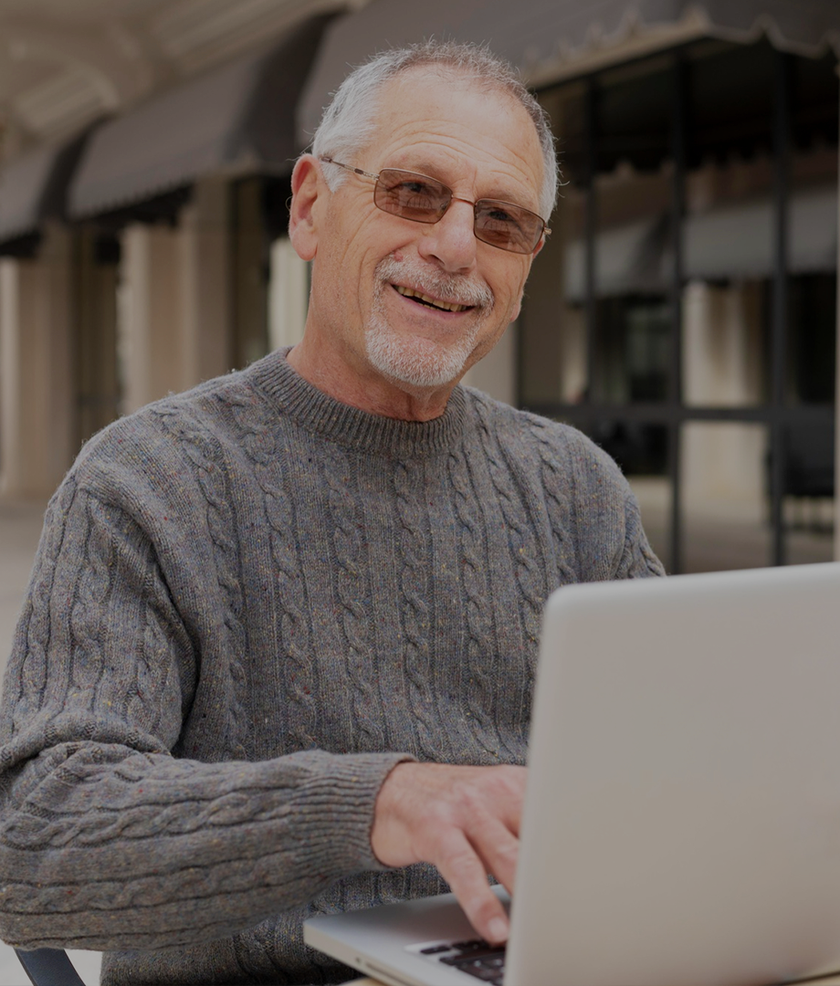 Man using a laptop outdoors with a blurred background