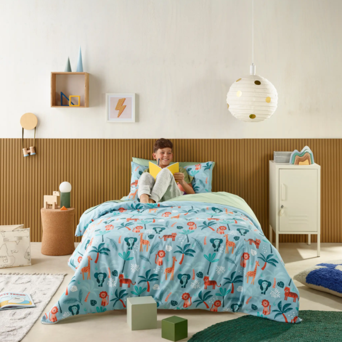Child sitting on a bed with colorful bedding in a bright bedroom
