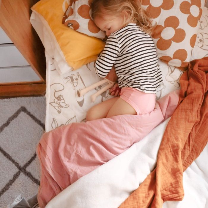 Child playing on a bed with colorful bedding and pillows