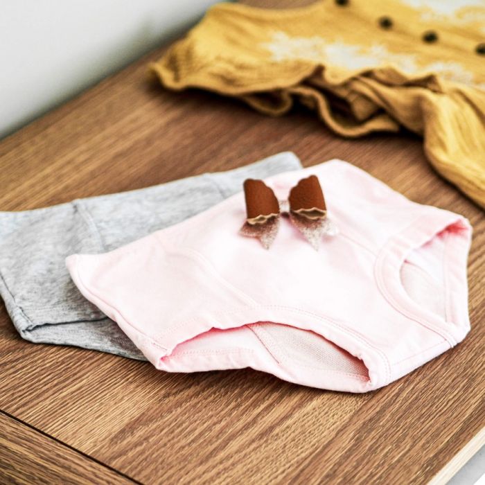 Pink baby outfit with a bow on a wooden surface