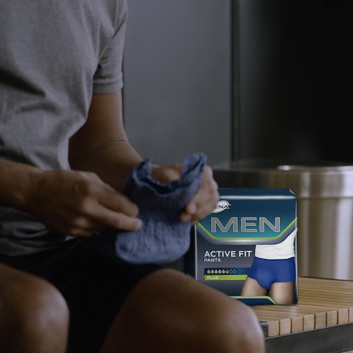 Person holding a blue sock with a box of Hanes Men's Active Fit Pants in the foreground.